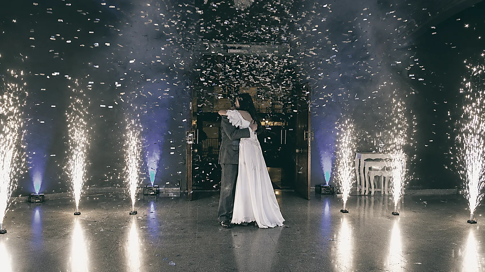 Los novios abrazados entre fuentes de chispas y confeti